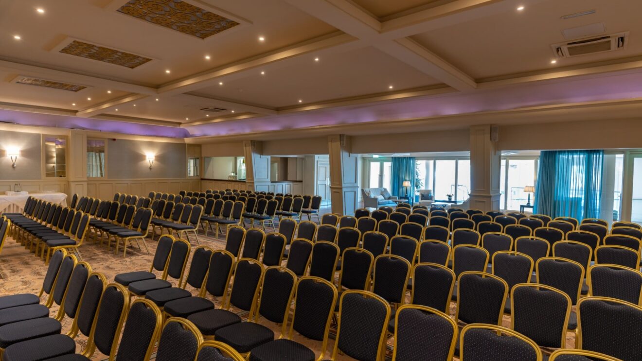 Spacious conference hall with elegant seating, ambient lighting, and natural daylight, ideal for events and meetings.