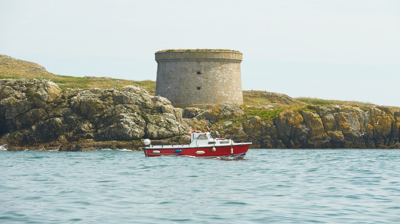 Red fishing boat in the sea with Lambay Island in background. La