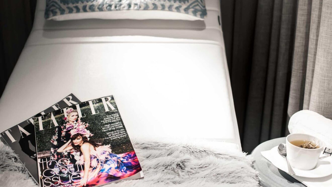 Cosy lounge area with plush throw, fashion magazines, and a warm teacup, perfect for relaxing in style and comfort.