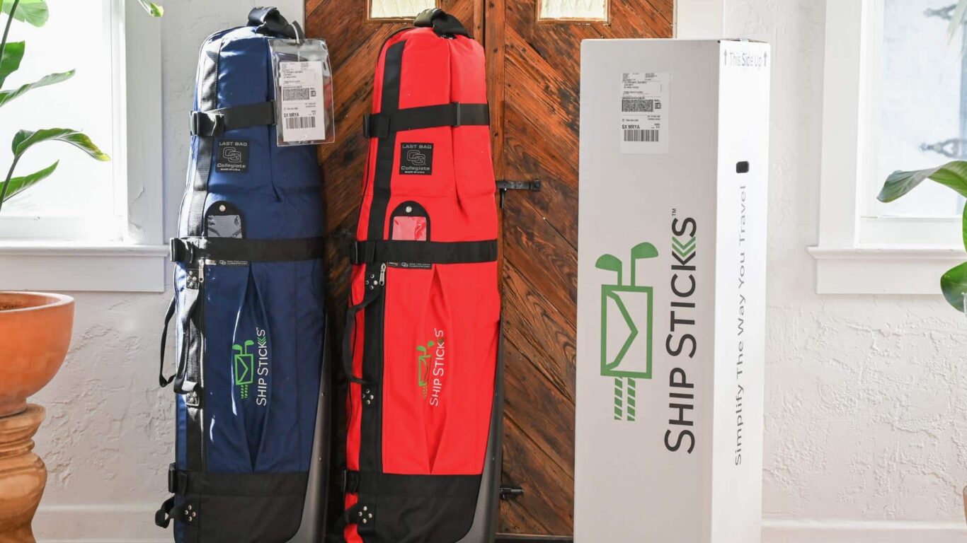 Sleek blue and red golf bags with Ship Sticks branding stand beside a wooden door in a bright, welcoming hotel lobby.
