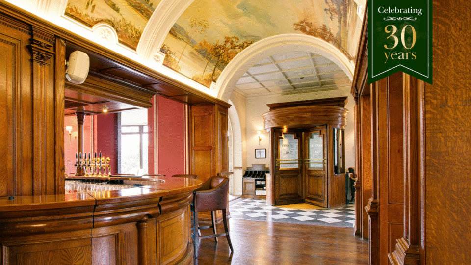 Elegant hotel bar with classic wooden decor, muraled arches, and charming seating, perfect for a welcoming drink.