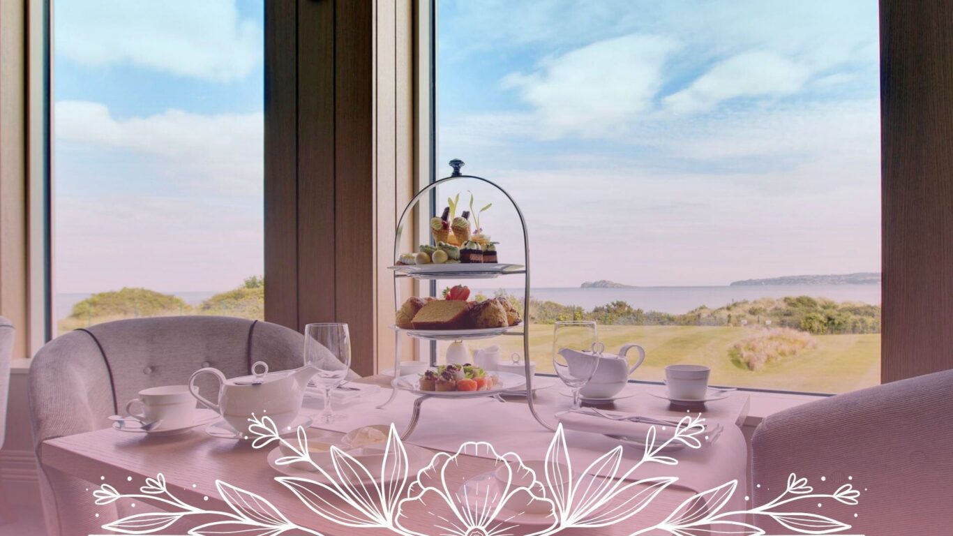 Elegant afternoon tea setup by window overlooking coastal scenery; savour delightful pastries with sea views.