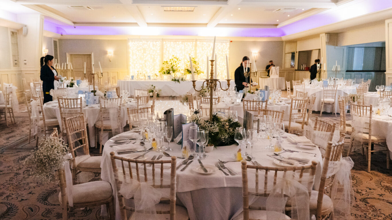 Elegant wedding venue with round tables, floral centrepieces, and ambient lighting, perfect for memorable celebrations.