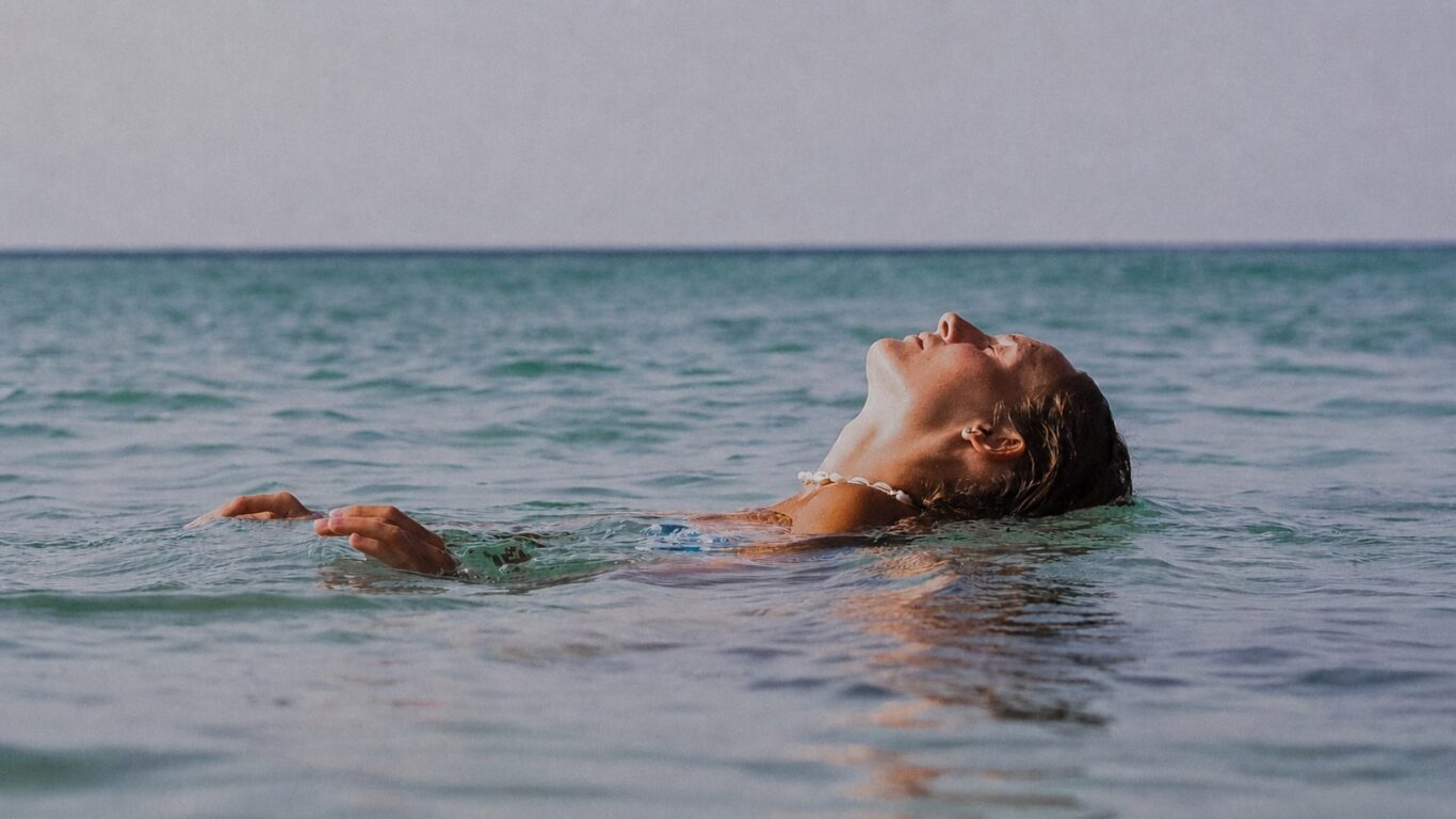 Serene guest floating in crystal-clear sea, enjoying luxurious seaside retreat with pristine ocean views and relaxation.