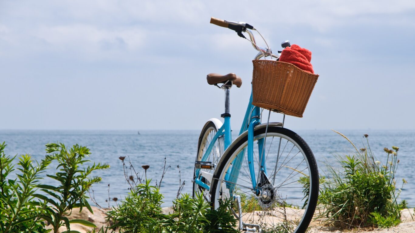 Enjoy a seaside bike ride with ocean views, bright blue skies and lush greenery, perfect for a refreshing retreat.