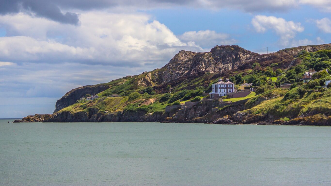 Coastal hotel nestled on lush cliffs overlooking serene sea, ideal for tranquil retreats and scenic views.