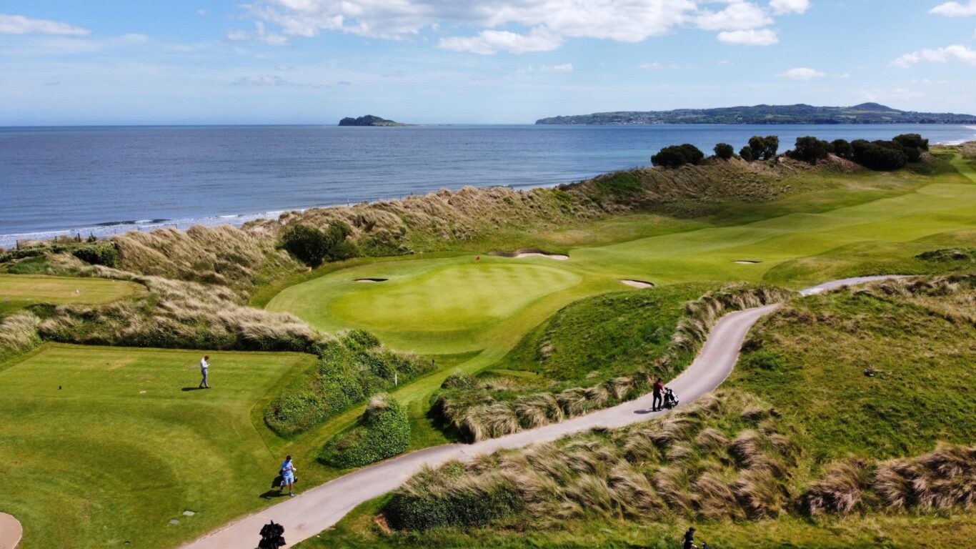 Scenic view of lush coastal golf course with ocean backdrop, ideal for relaxing and golfing holidays.