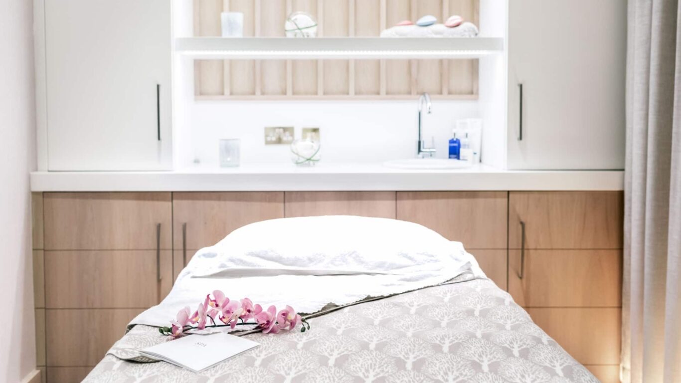 Tranquil spa treatment room with massage bed, orchids, soft lighting, and modern amenities at luxury hotel.