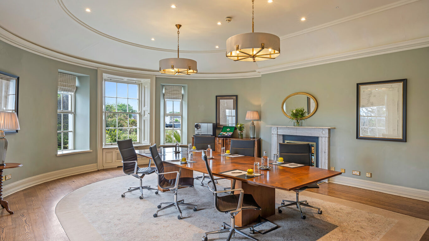 Elegant hotel meeting room with large windows, modern chairs, and stylish chandelier, ideal for business gatherings.