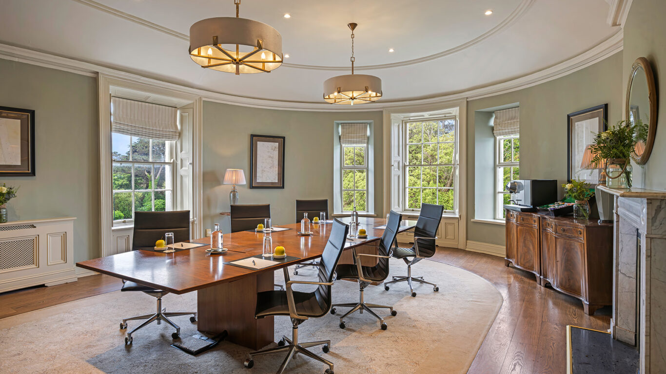 Elegant meeting room with large windows, lush garden view, modern chairs, and conference table perfect for business events.