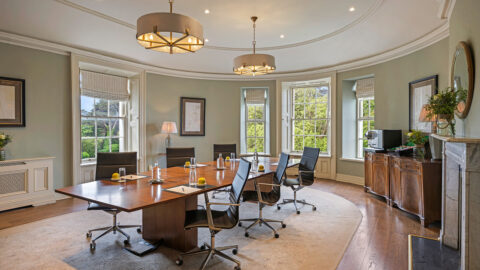 Elegant meeting room with large windows, lush garden view, modern chairs, and conference table perfect for business events.