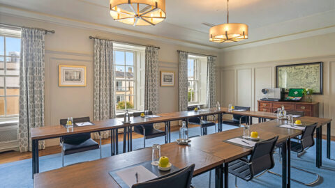 Bright conference room with elegant decor, large windows, modern chairs, U-shaped tables, and ample natural light.