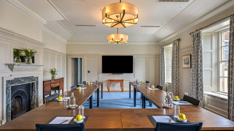 Elegant meeting room with modern amenities, natural light, and cosy fireplace at a British hotel, perfect for events.
