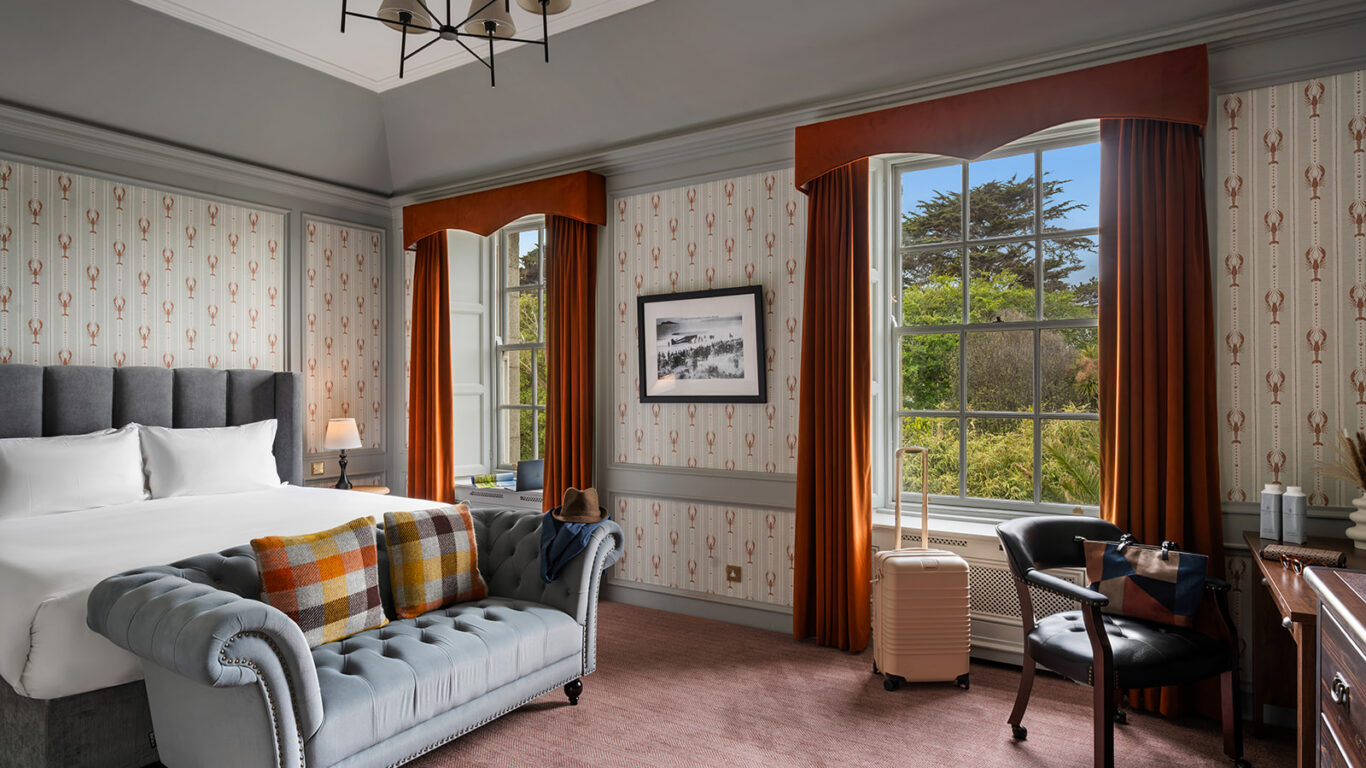 Elegant hotel room with king bed, plush sofa, large window with garden view, and stylish decor. Perfect for a relaxing stay.
