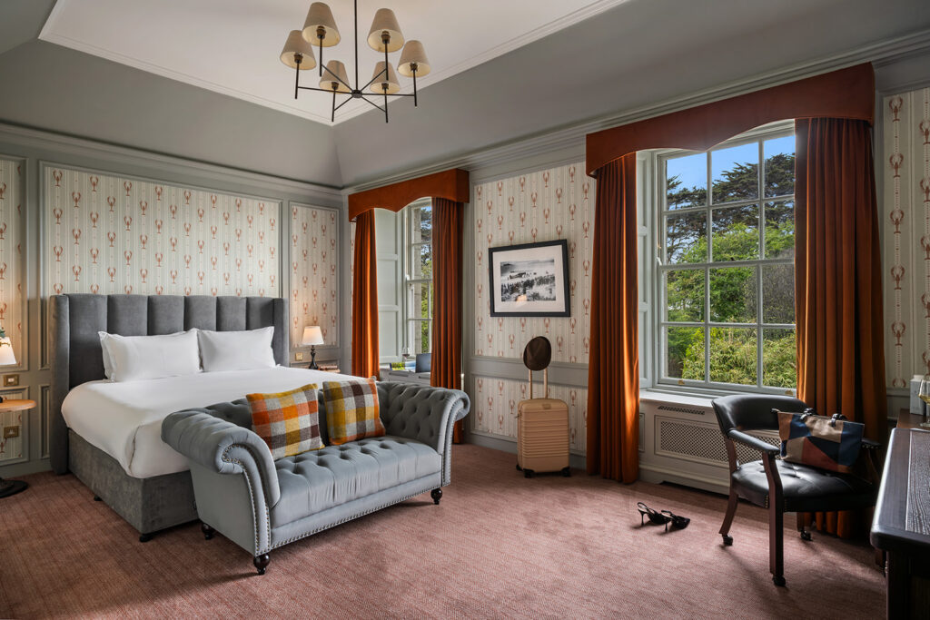 Luxurious Hotel Room with Garden View Elegant hotel room with plush bed, stylish armchair, and large window overlooking lush garden; cosy and inviting.
