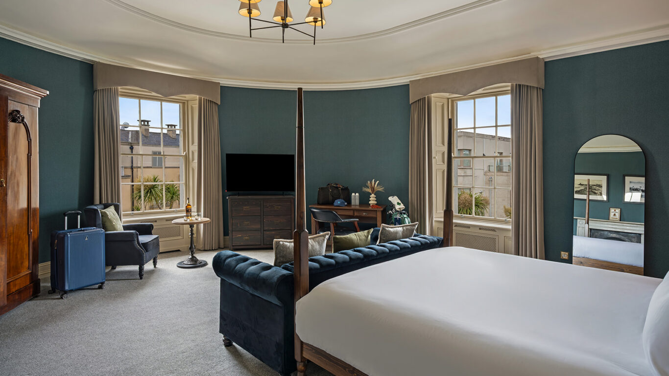 Elegant hotel room with luxurious bed, classic furnishings, large windows with city views, and modern amenities. Perfect for relaxing.