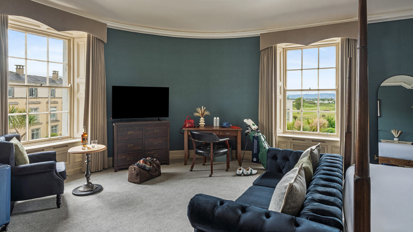 Spacious hotel room with sea view, elegant furnishings, luxurious sofa, and golf gear. Perfect for relaxation and leisure.