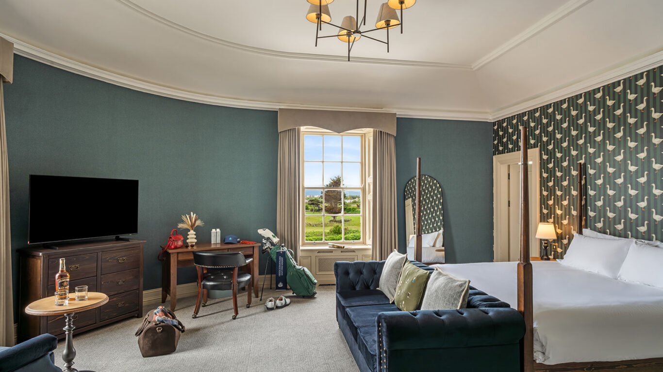 Elegant hotel room with a plush bed, stylish decor, cosy seating, and a window view of lush gardens. Relax and unwind.