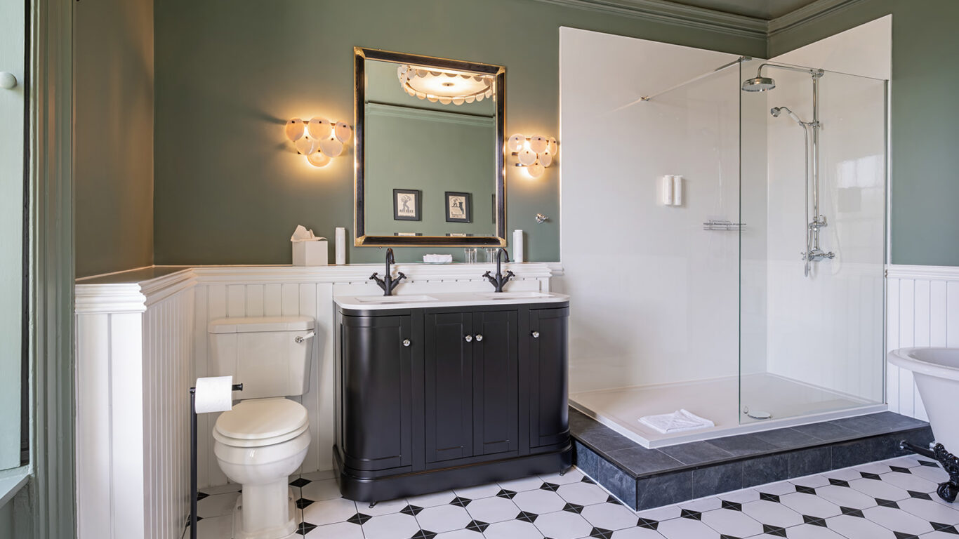 Elegant bathroom with spacious walk-in shower, vintage-style sink, and soft lighting; ideal for relaxation at our hotel.