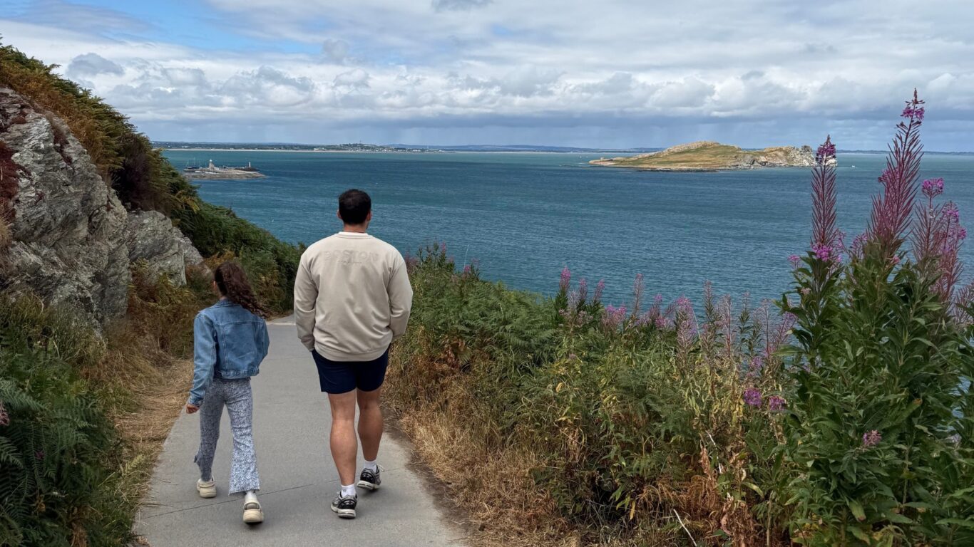 Guests enjoy a scenic coastal walk with stunning ocean views, vibrant wildflowers, and lush greenery at a seaside retreat.