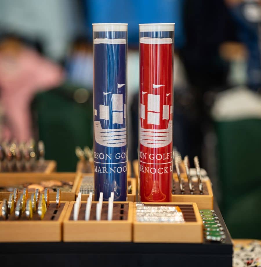 Elegant Golf Souvenir Display Luxurious wooden golf tee display at hotel shop, showcasing blue and red branded tubes for an elegant golfing experience.