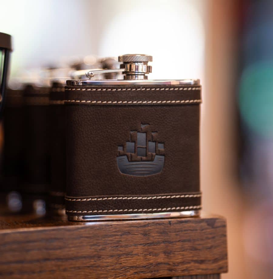 Elegant Leather Hip Flask Display Stylish brown leather hip flask with embossed ship, offering a touch of luxury and elegance at our welcoming hotel.