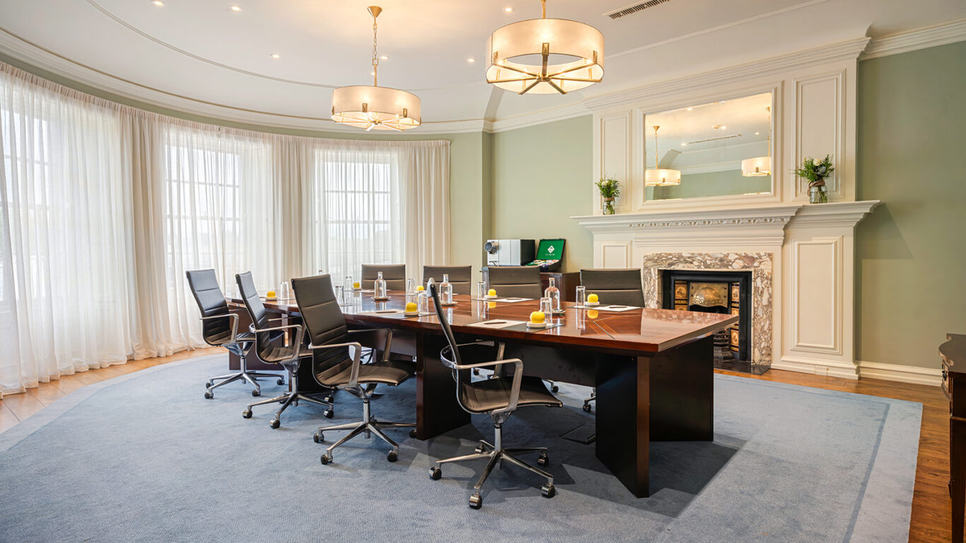 Elegant hotel conference room with cosy fireplace, plush chairs, and natural light, perfect for meetings in a professional setting.