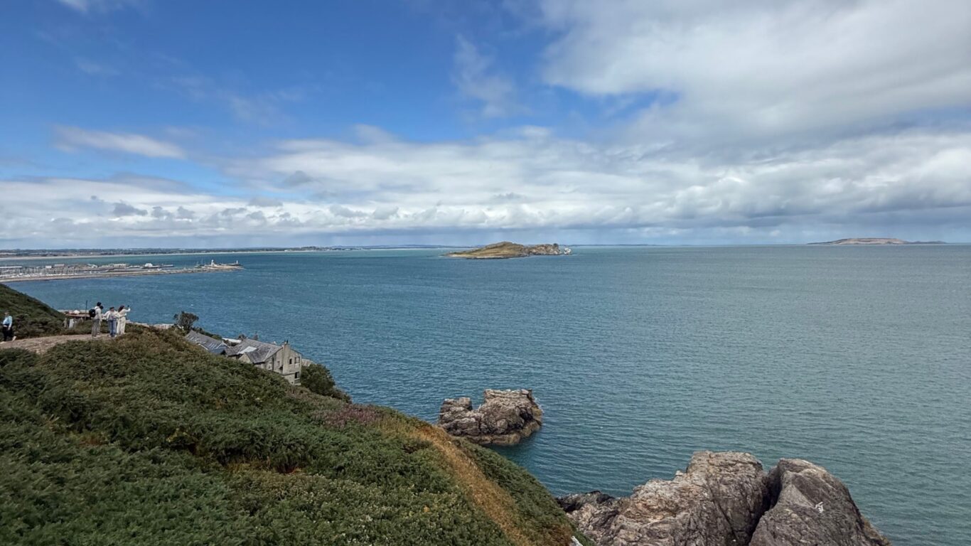 Spectacular coastal view from hotel, azure ocean meeting dramatic cliffs under a vast sky, ideal for serene getaways.
