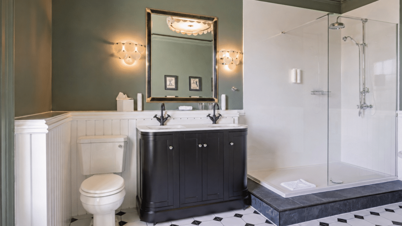 Elegant bathroom with walk-in shower, stylish double sink, and vintage lighting in a luxury hotel suite.
