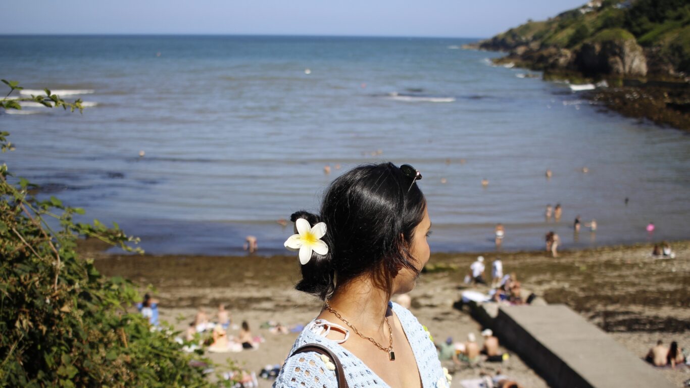 Woman enjoying sunny beach views, with soft sand and gentle waves, offering a relaxing seaside holiday experience.