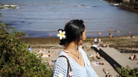 Woman enjoying sunny beach views, with soft sand and gentle waves, offering a relaxing seaside holiday experience.